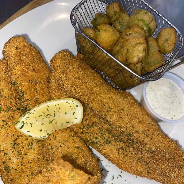Catfish Willy's fried catfish fillets with a lemon wedge, fried okra, and tartar sauce.