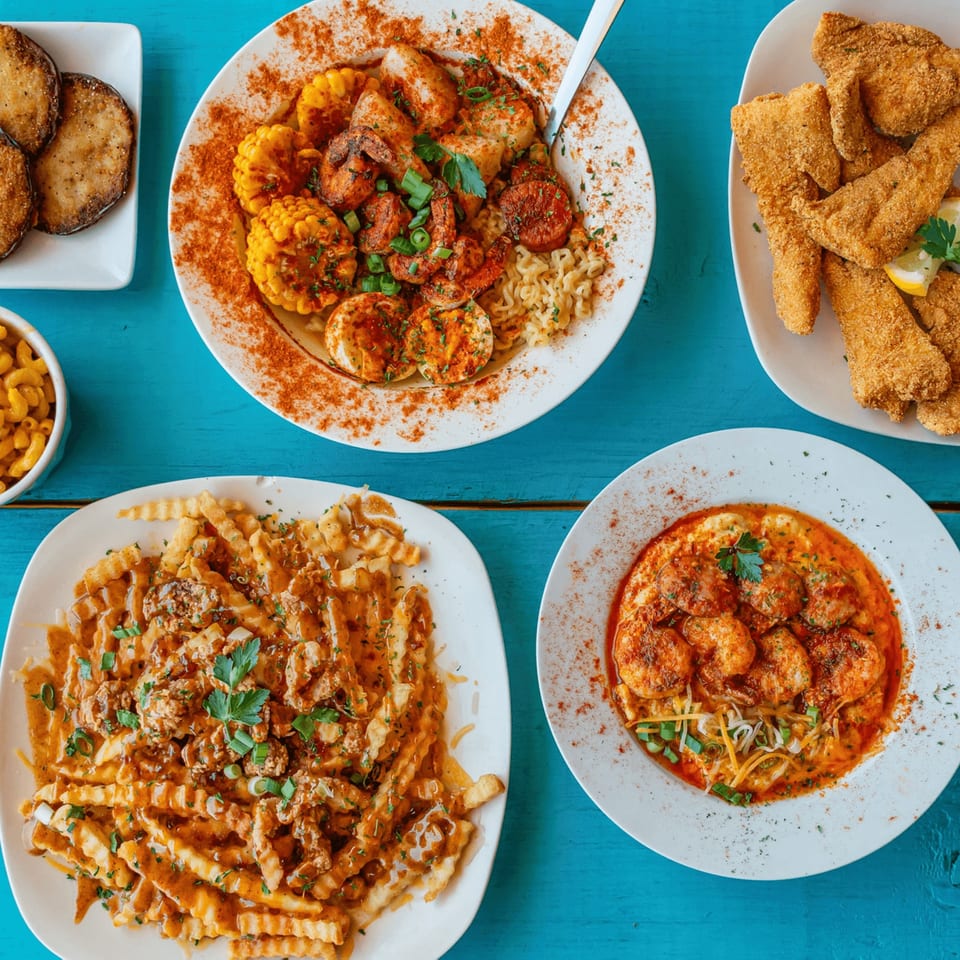 An overhead view of various seafood dishes, including fried fish, shrimp, and fries, on a blue table.