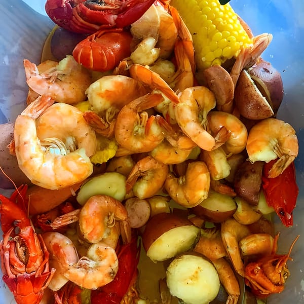 A close-up of a seafood boil with shrimp, crawfish, corn on the cob, and potatoes.