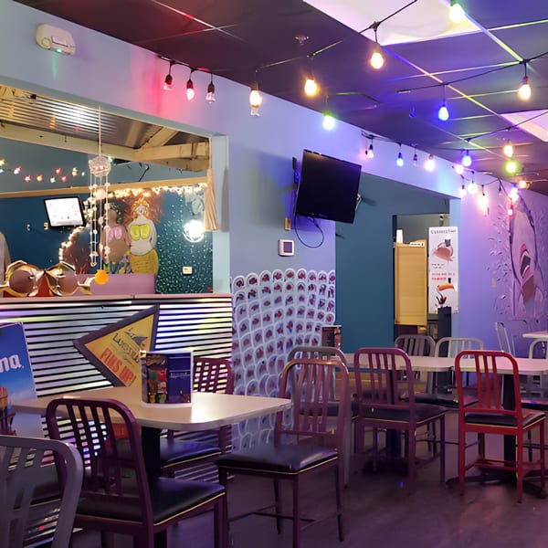 Interior of Catfish Willy's, featuring colorful string lights, tables, chairs, and mermaid decor.
